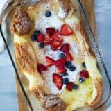 top view of Dutch baby in a glass baking dish with berries