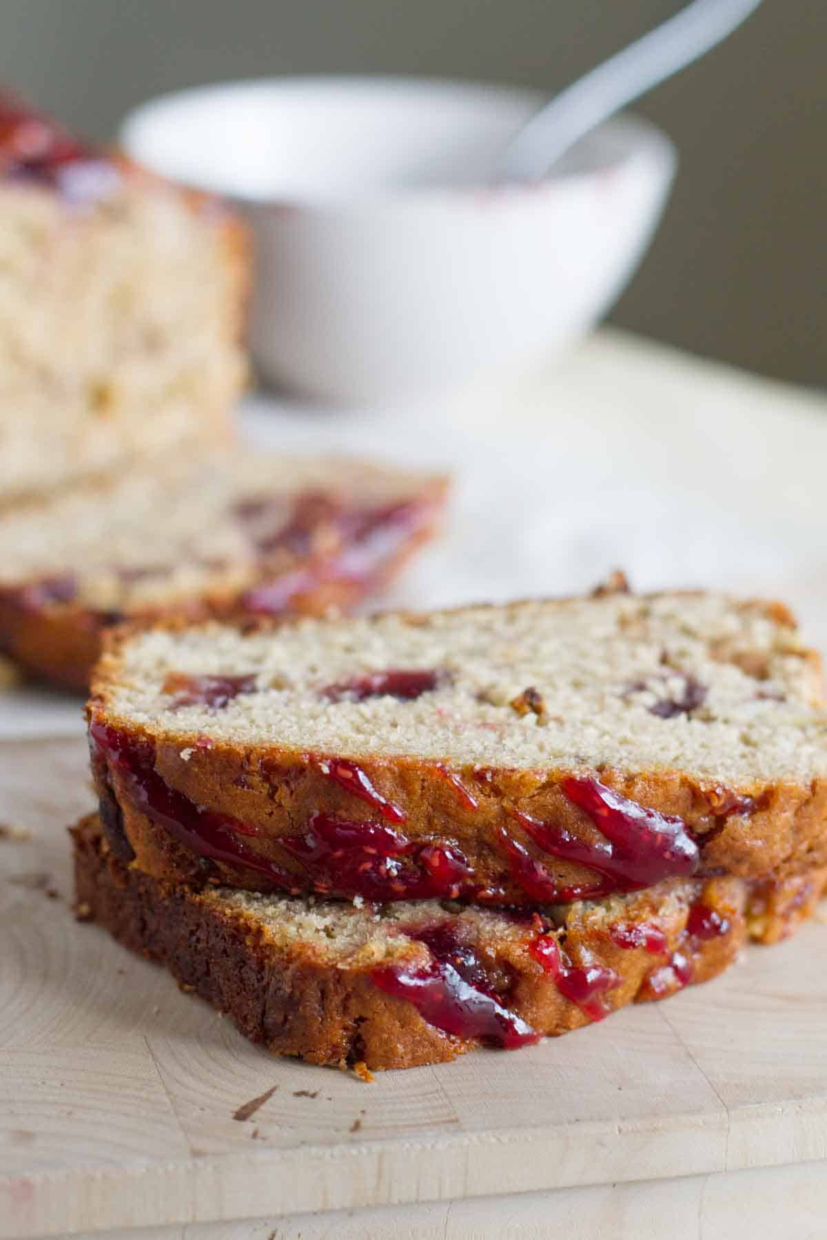 Two slices of Peanut Butter and Jelly Banana Bread on a wooden board.