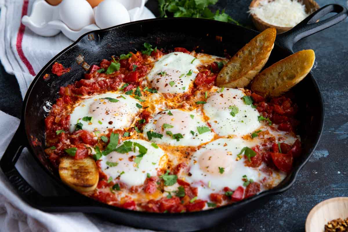 Shakshuka with crusty bread in a cast iron skillet