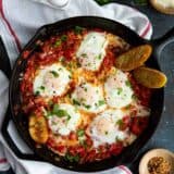 Cast iron skillet with eggs poached in tomato sauce for shakshuka
