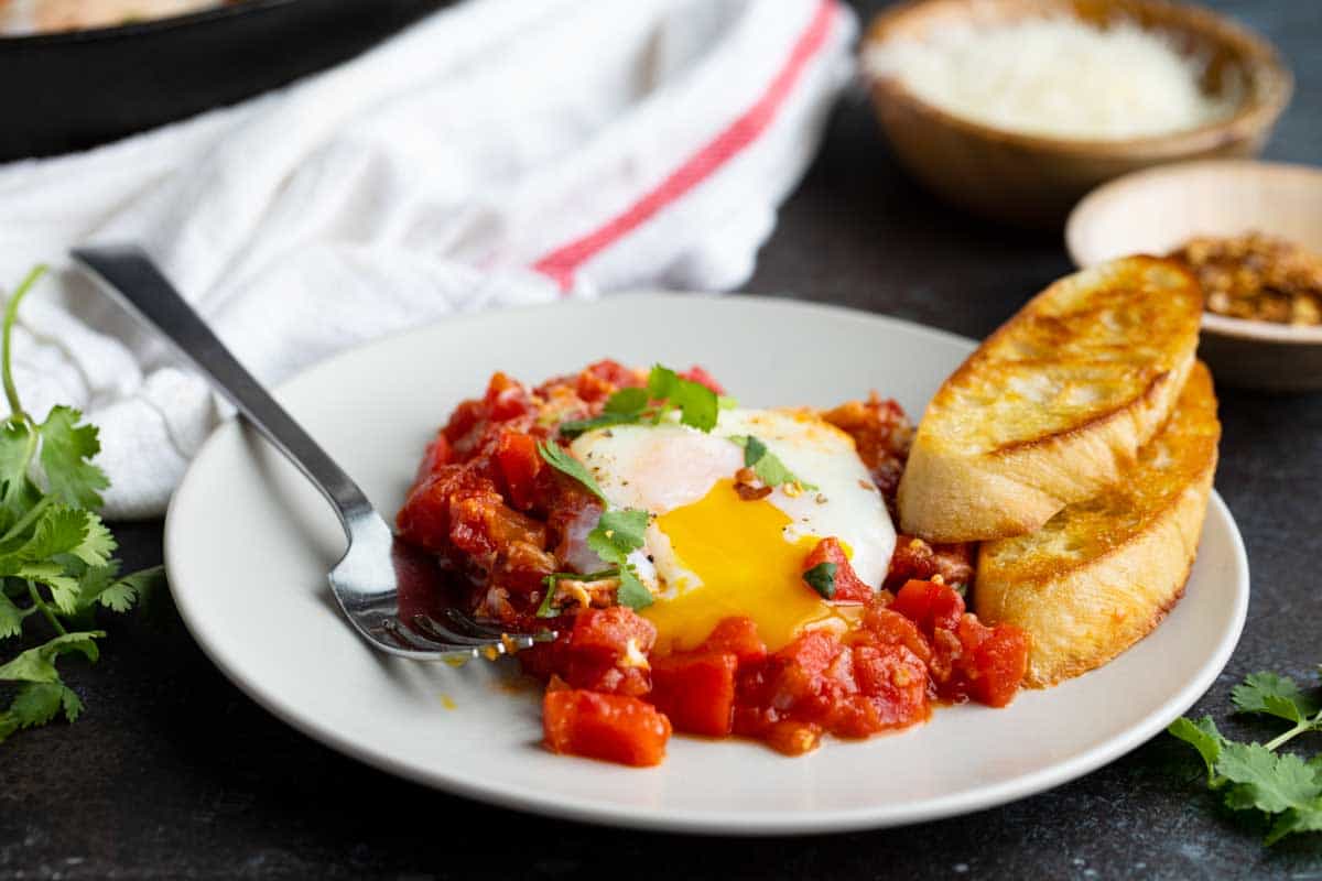 plate with shakshuka and crusty bread