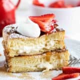 Stuffed French Toast cut and stacked topped with strawberries, whipped cream, and powdered sugar