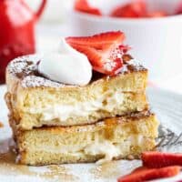 Stuffed French Toast cut and stacked topped with strawberries, whipped cream, and powdered sugar
