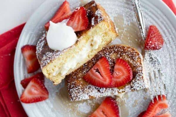 Stuffed French Toast cut in half showing filling, topped with strawberries