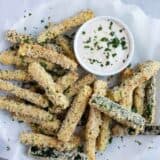 baked zucchini fries stacked on parchment paper