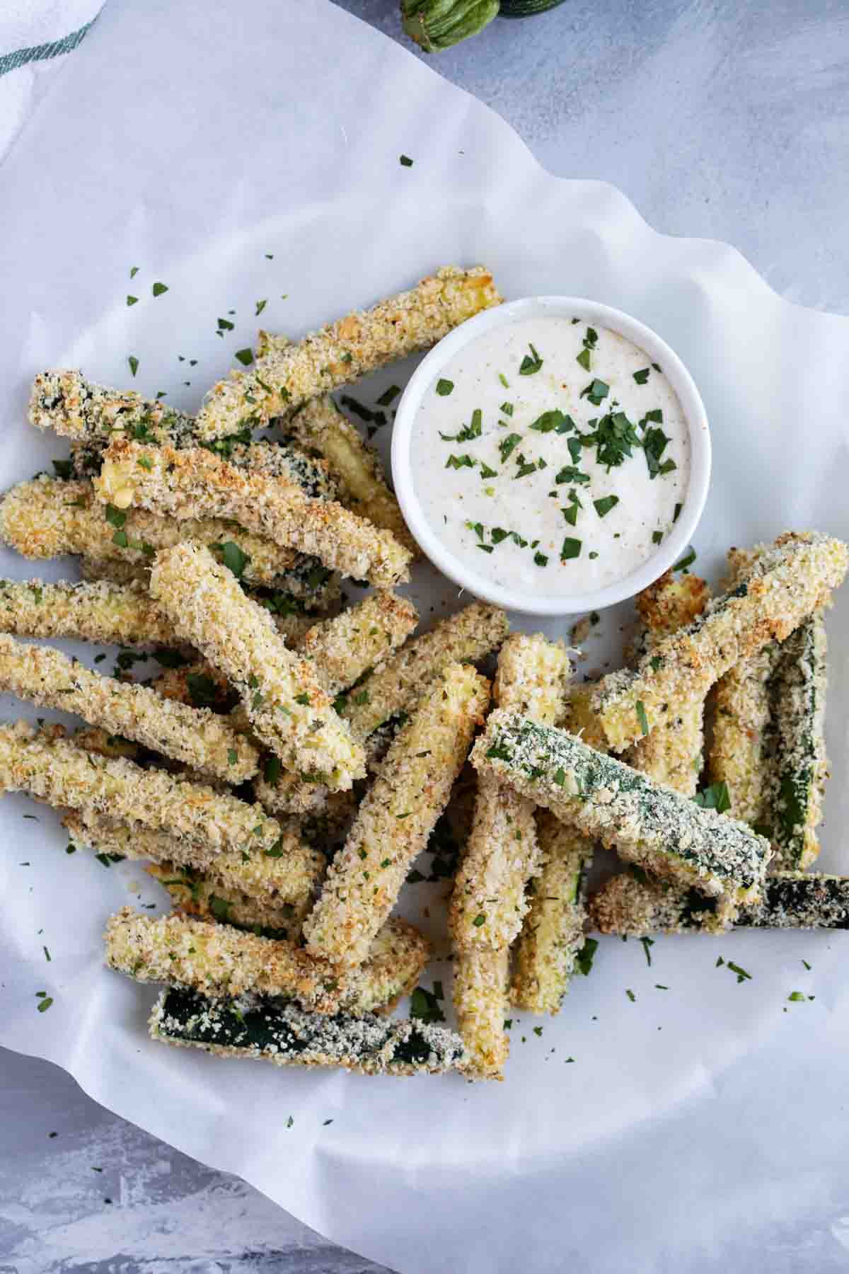 baked zucchini fries stacked on parchment paper