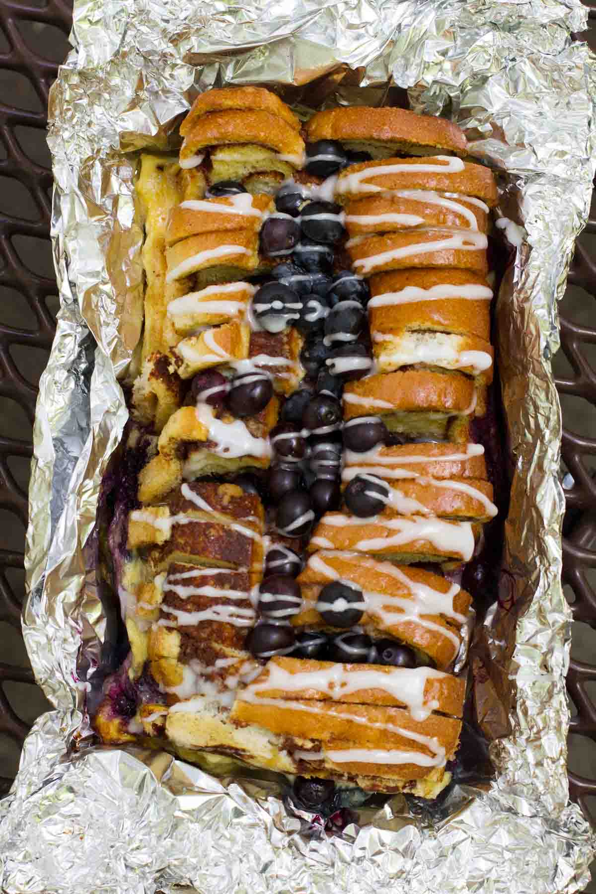 view of campfire cinnamon blueberry bread topped with glaze and blueberries.