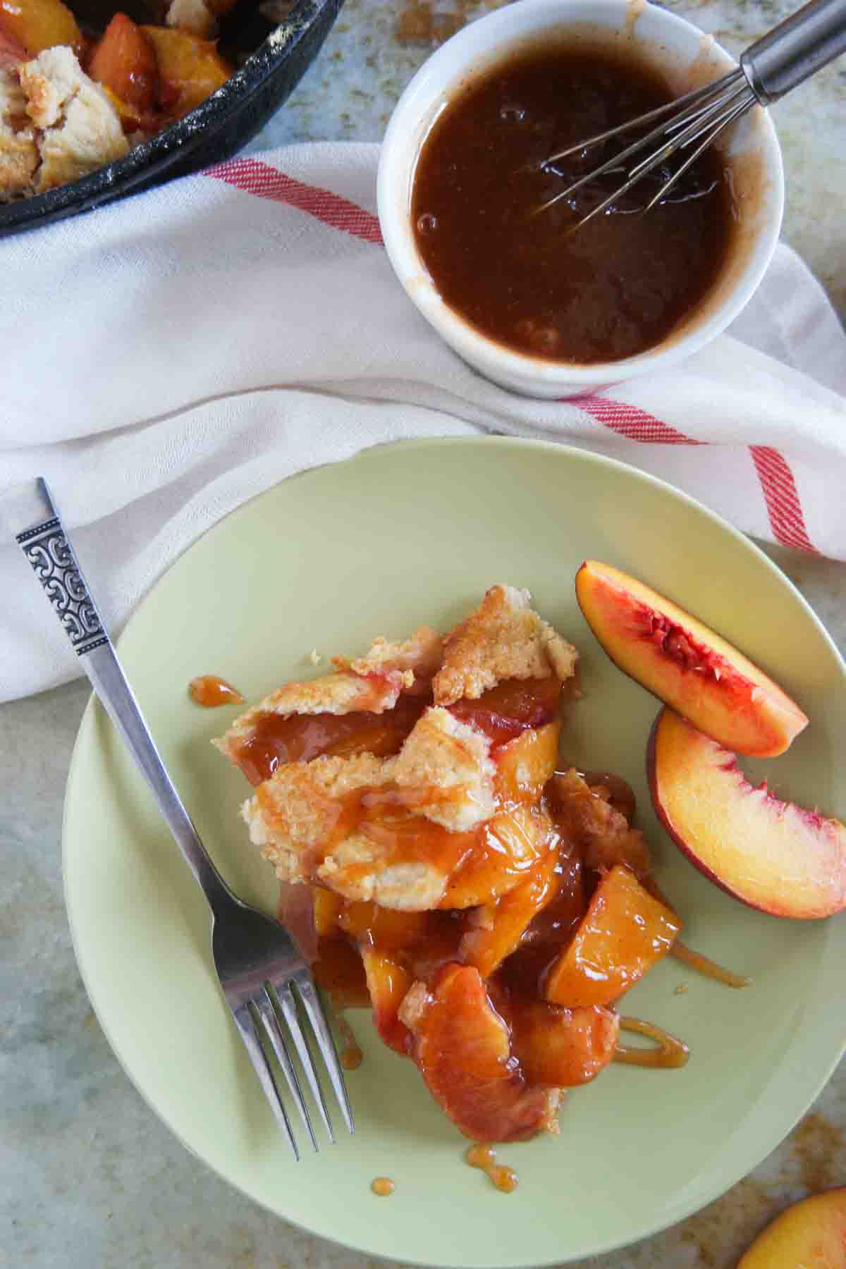 slice of Cast Iron Peach Crostata with sauce spooned over the top