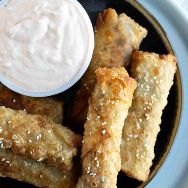 Plate with Cheeseburger Eggrolls stacked with a dish of Russian dipping sauce