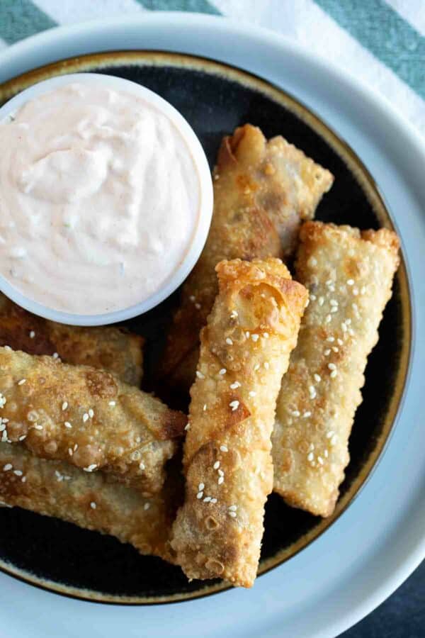 Plate with Cheeseburger Eggrolls stacked with a dish of Russian dipping sauce