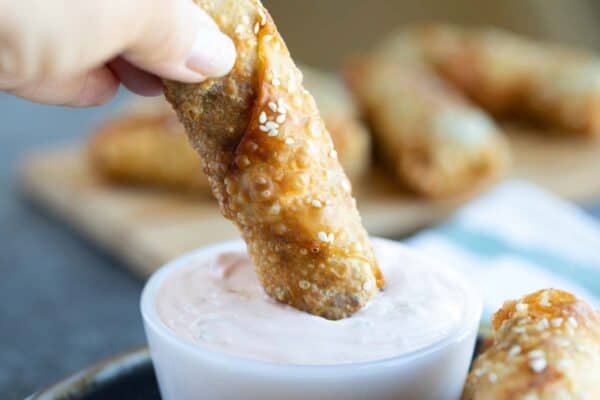 dipping a cheeseburger eggroll in dipping sauce