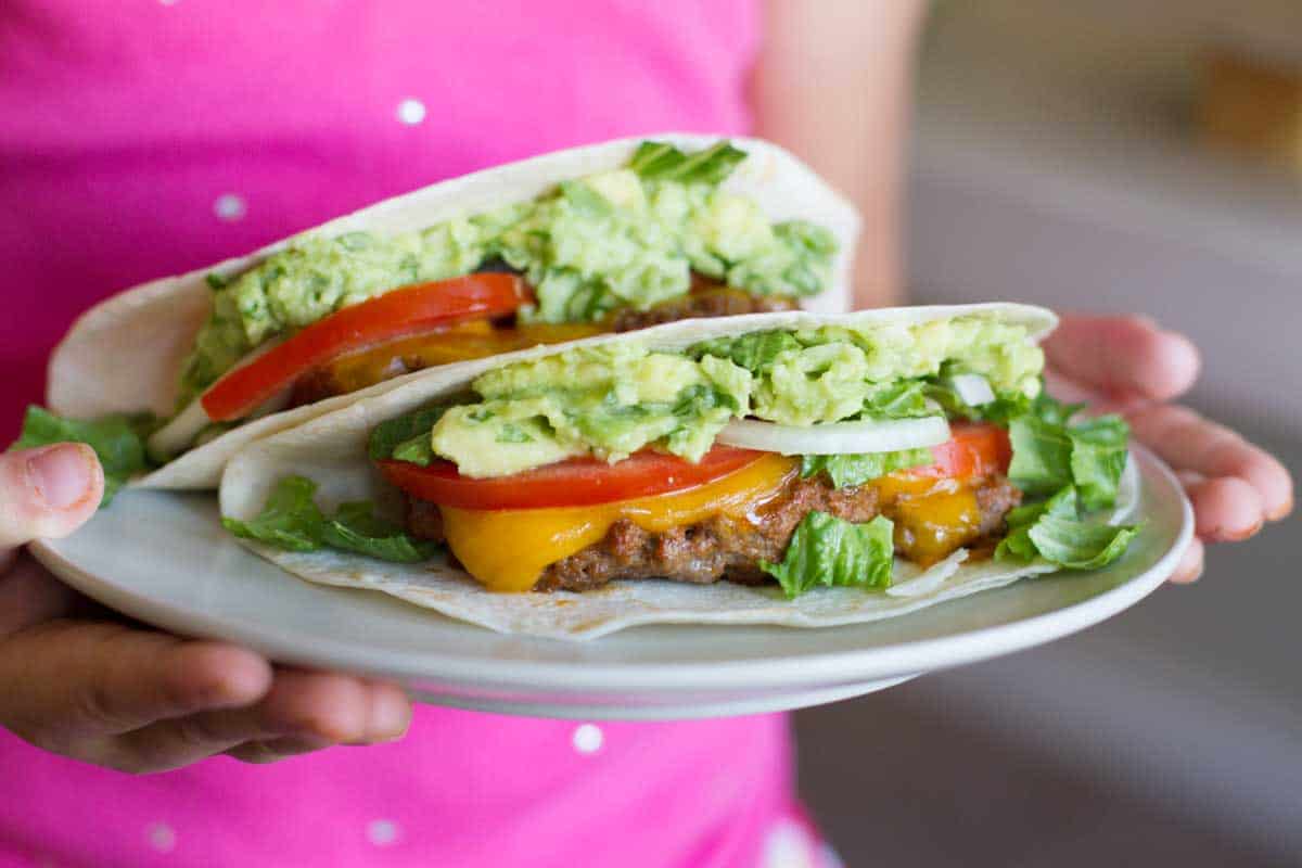 girl holding a plate with two Cheeseburger Tacos