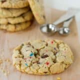 chocolate chip sprinkle cookie on a cutting board with more behind