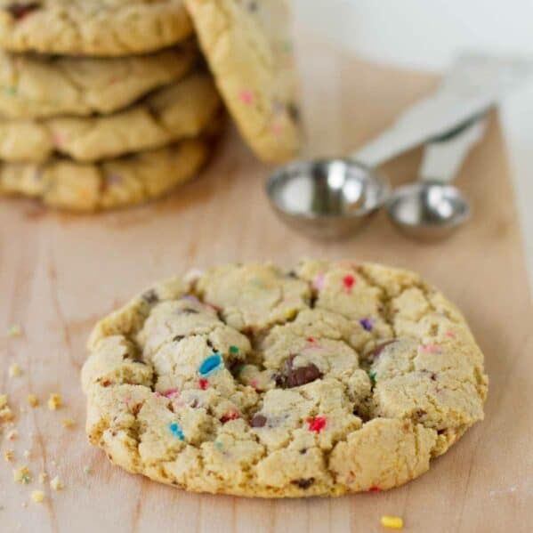 chocolate chip sprinkle cookie on a cutting board with more behind