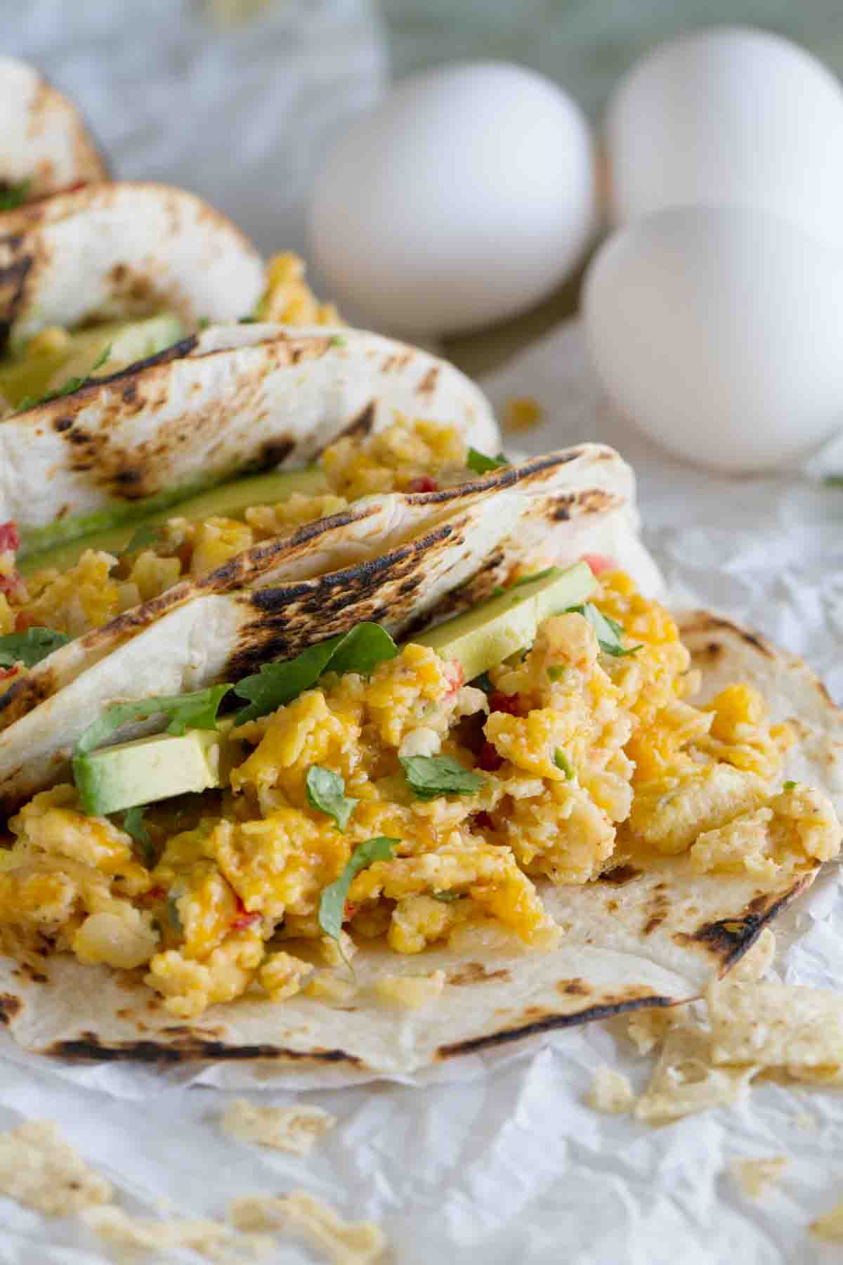 Eat your tacos for breakfast with these Migas Tacos filled with scrambled eggs with onions, jalapeños, tomatoes and crumbled tortilla chips. They are a great way to add a little Tex-Mex to your morning! Migas tacos with avocado on flour tortillas