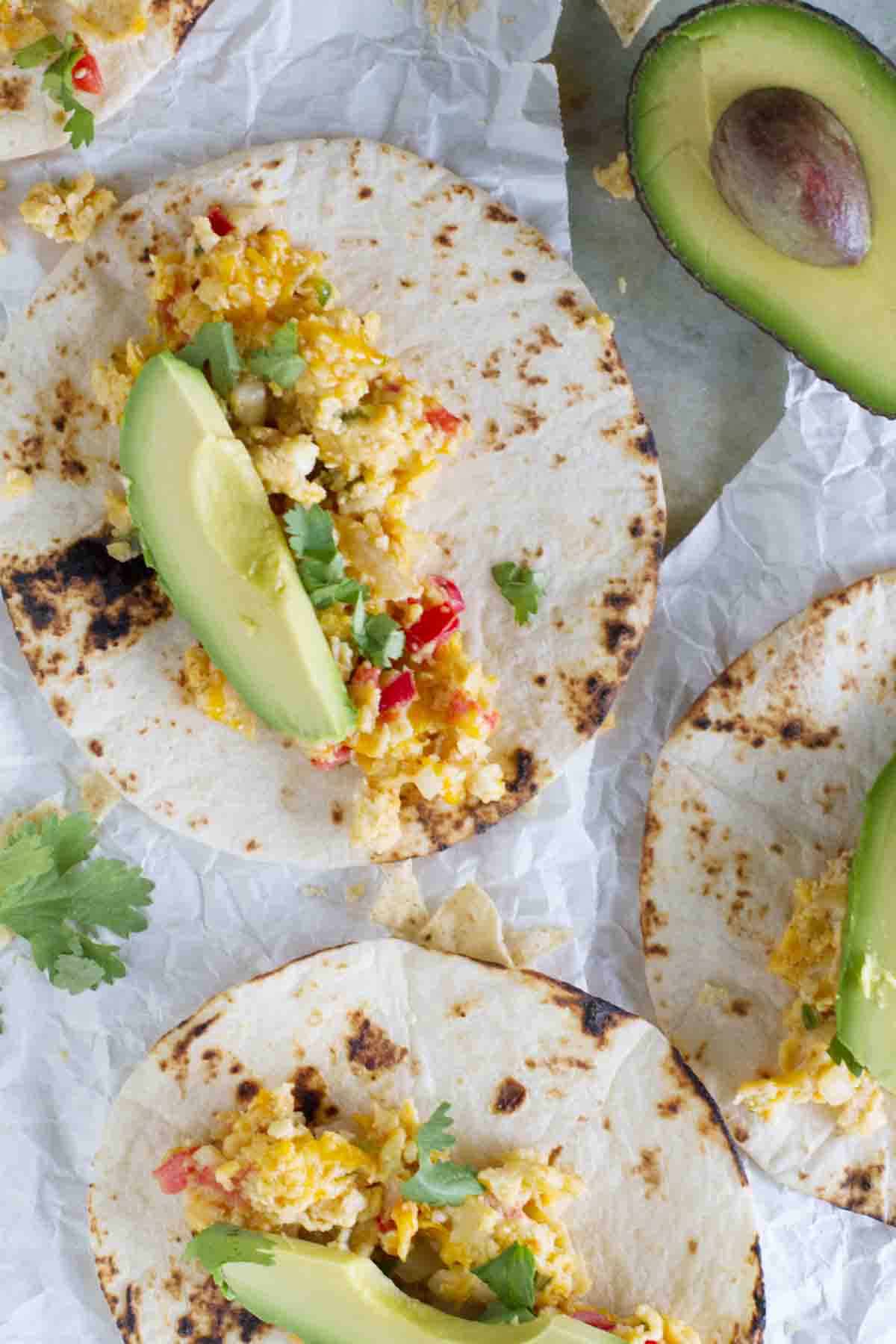 tortillas topped with eggs, tomatoes, tortilla chips, and avocado.