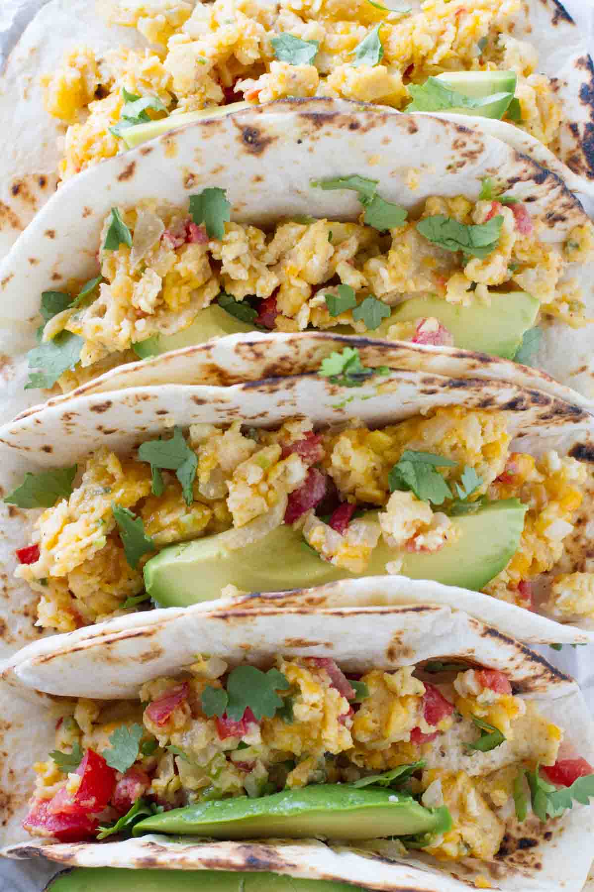 Eat your tacos for breakfast with these Migas Tacos filled with scrambled eggs with onions, jalapeños, tomatoes and crumbled tortilla chips. They are a great way to add a little Tex-Mex to your morning! Migas tacos with avocado and cilantro