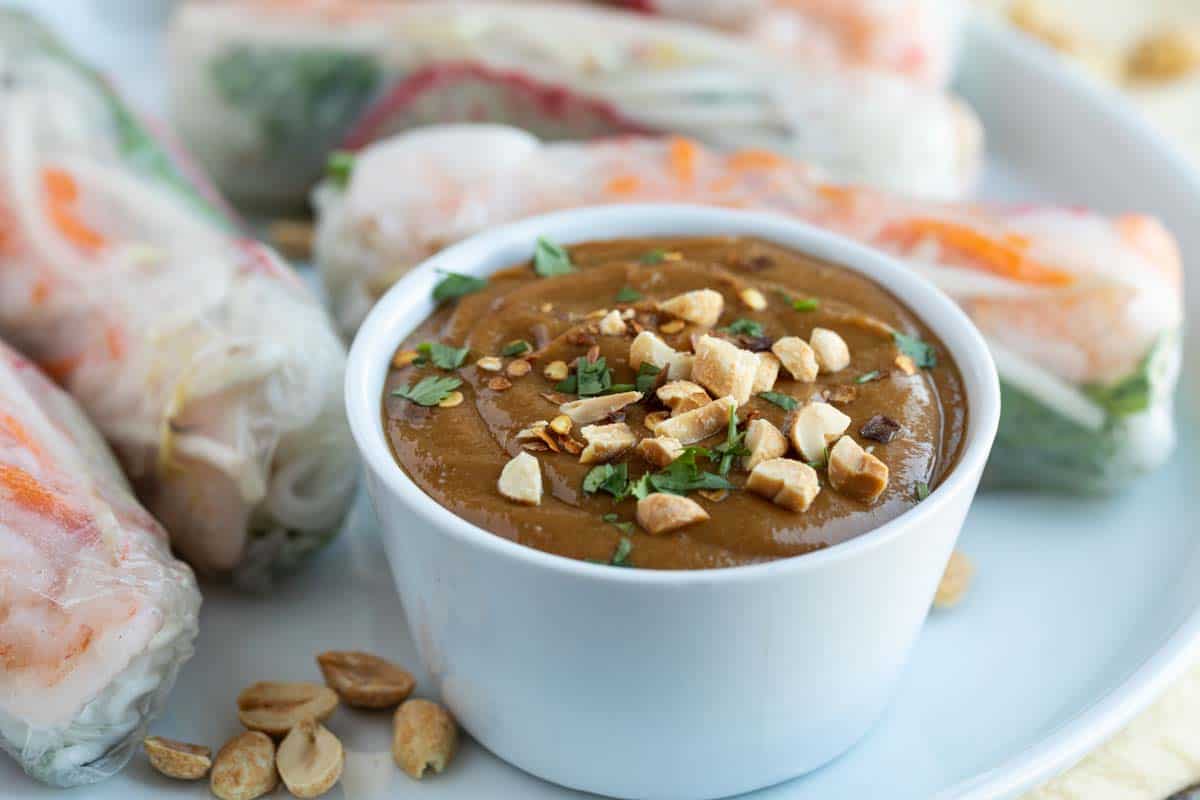 The perfect Peanut Sauce is only 10 minutes away! This sauce is so simple to make, yet so complex in flavor. It’s perfect for dipping or for dressing a salad or noodles. dish with Peanut Sauce on a plate with spring rolls