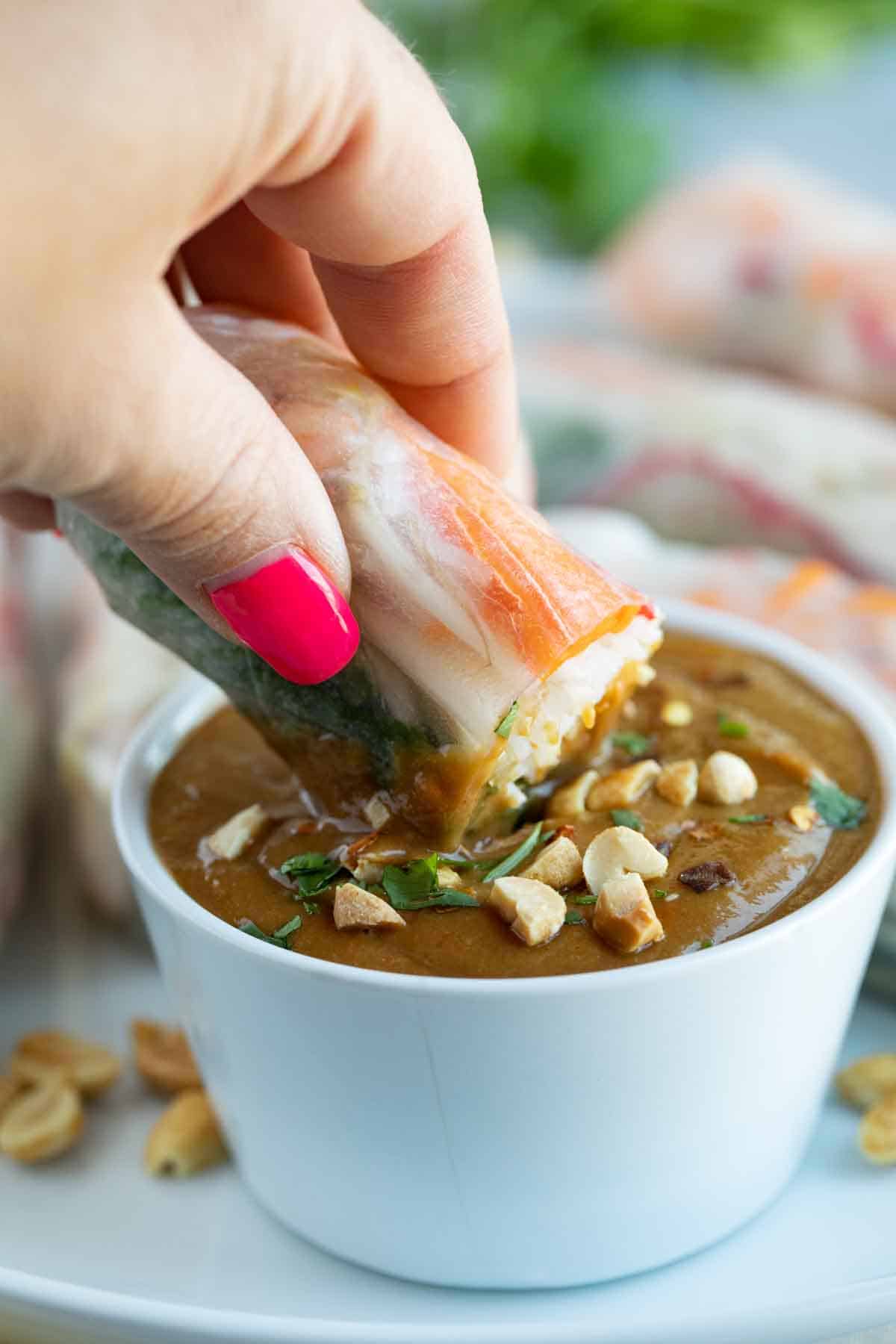 dipping a spring roll into Peanut Sauce
