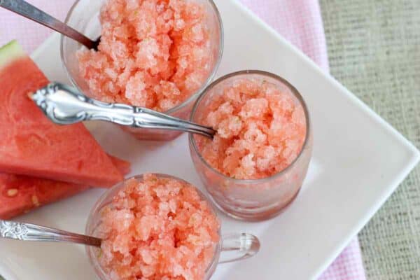 cups filled with watermelon granita with fresh watermelon on the side
