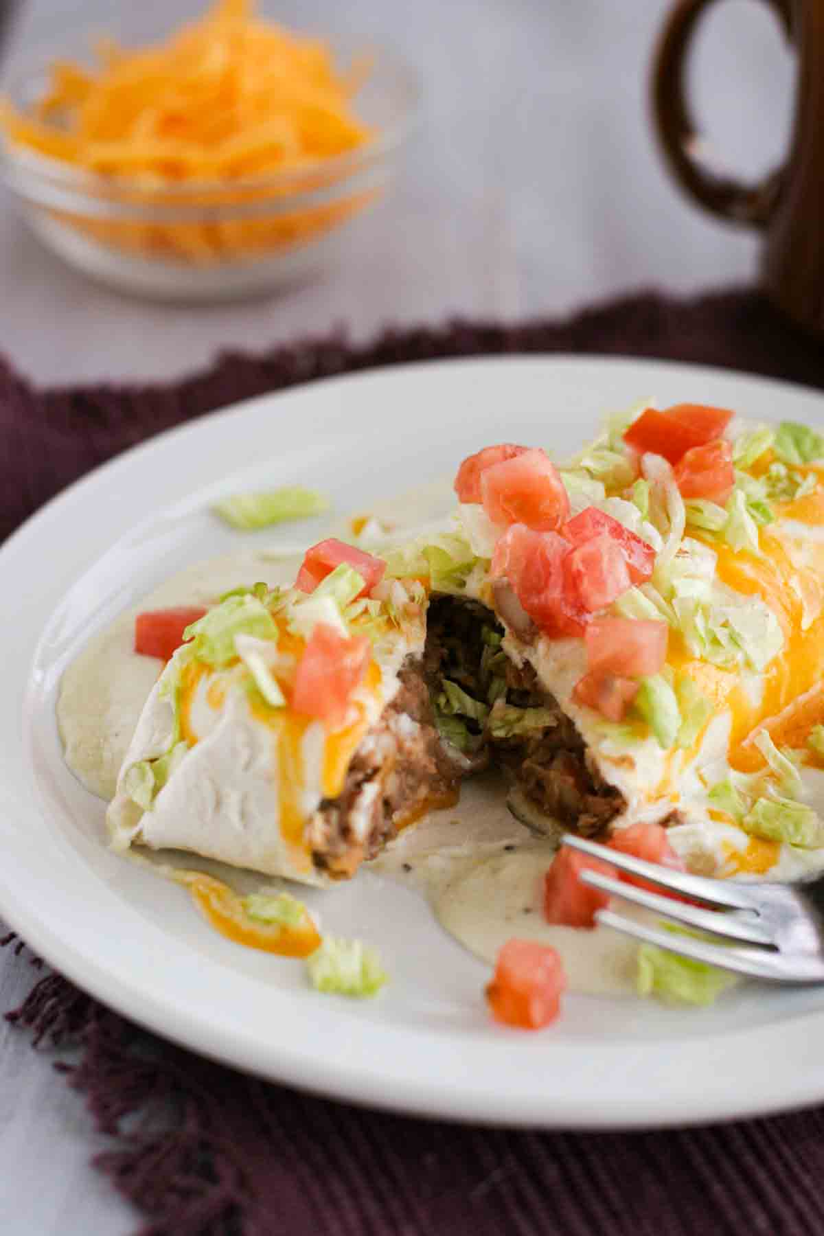 Beef and Bean Burrito smothered in green chile sauce cut open with a fork.