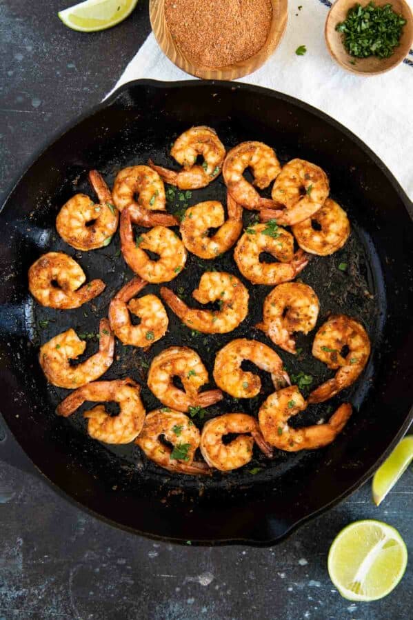 Cajun shrimp in a cast iron skillet with lime wedges.