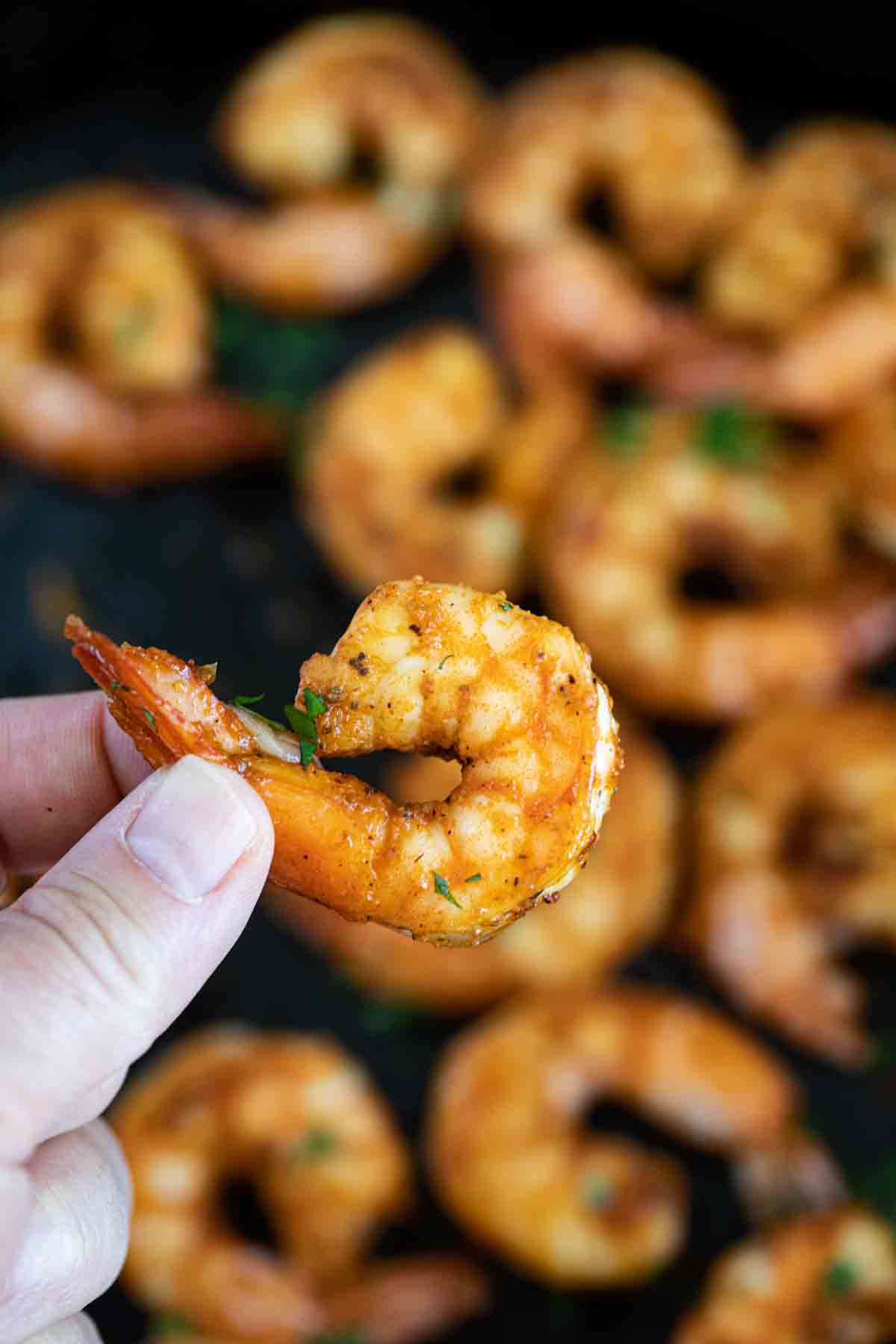fingers holding a single cajun shrimp.