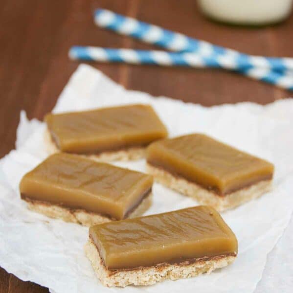 Four Chocolate Caramel Bars on white paper served with milk.