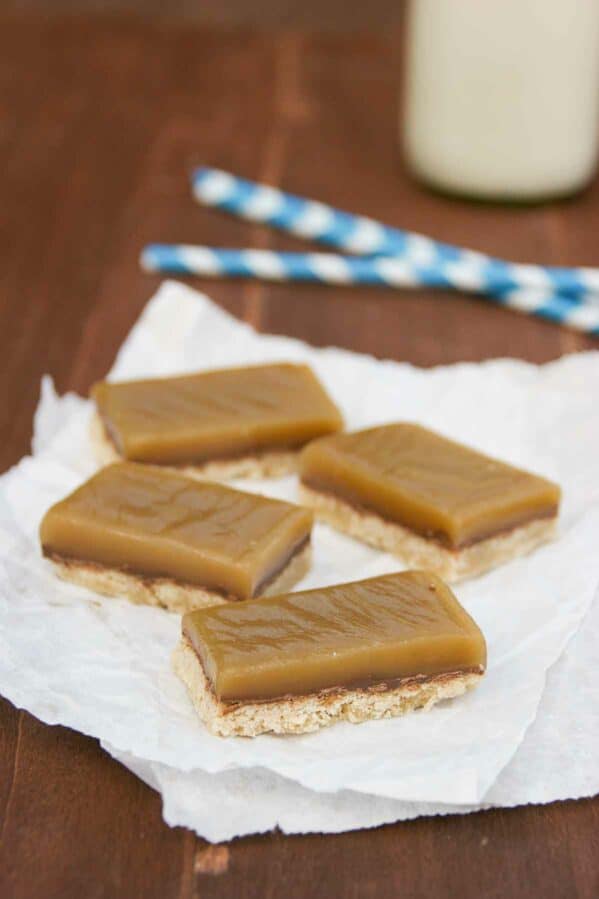 Four Chocolate Caramel Bars on white paper served with milk.