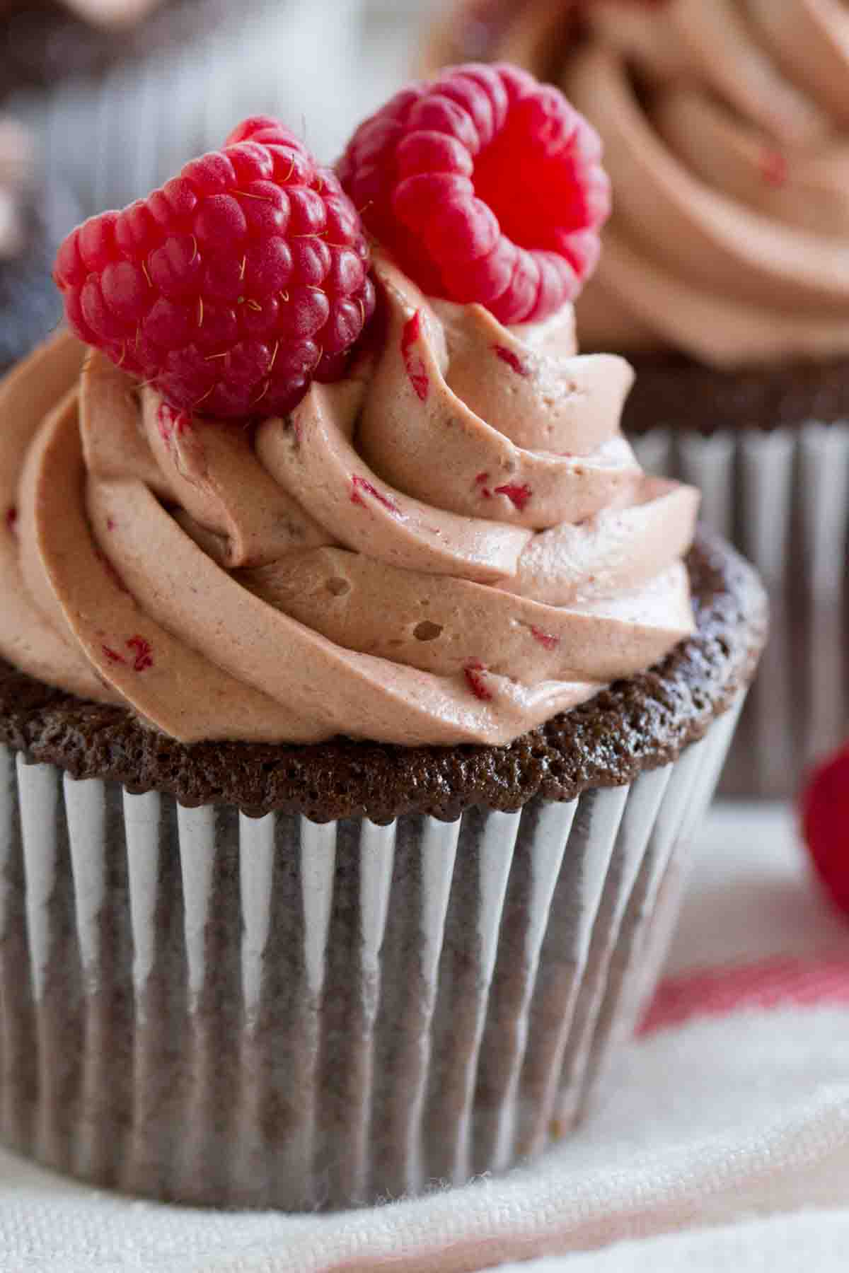 It doesn't get better than these Chocolate Cupcakes with Raspberry Filling! The perfect marriage of chocolate and raspberry – chocolate cupcakes are filled with a fresh raspberry filling, then topped with a silky smooth raspberry chocolate Swiss Meringue Buttercream. chocolate cupcake with raspberry filling topped with chocolate raspberry buttercream.