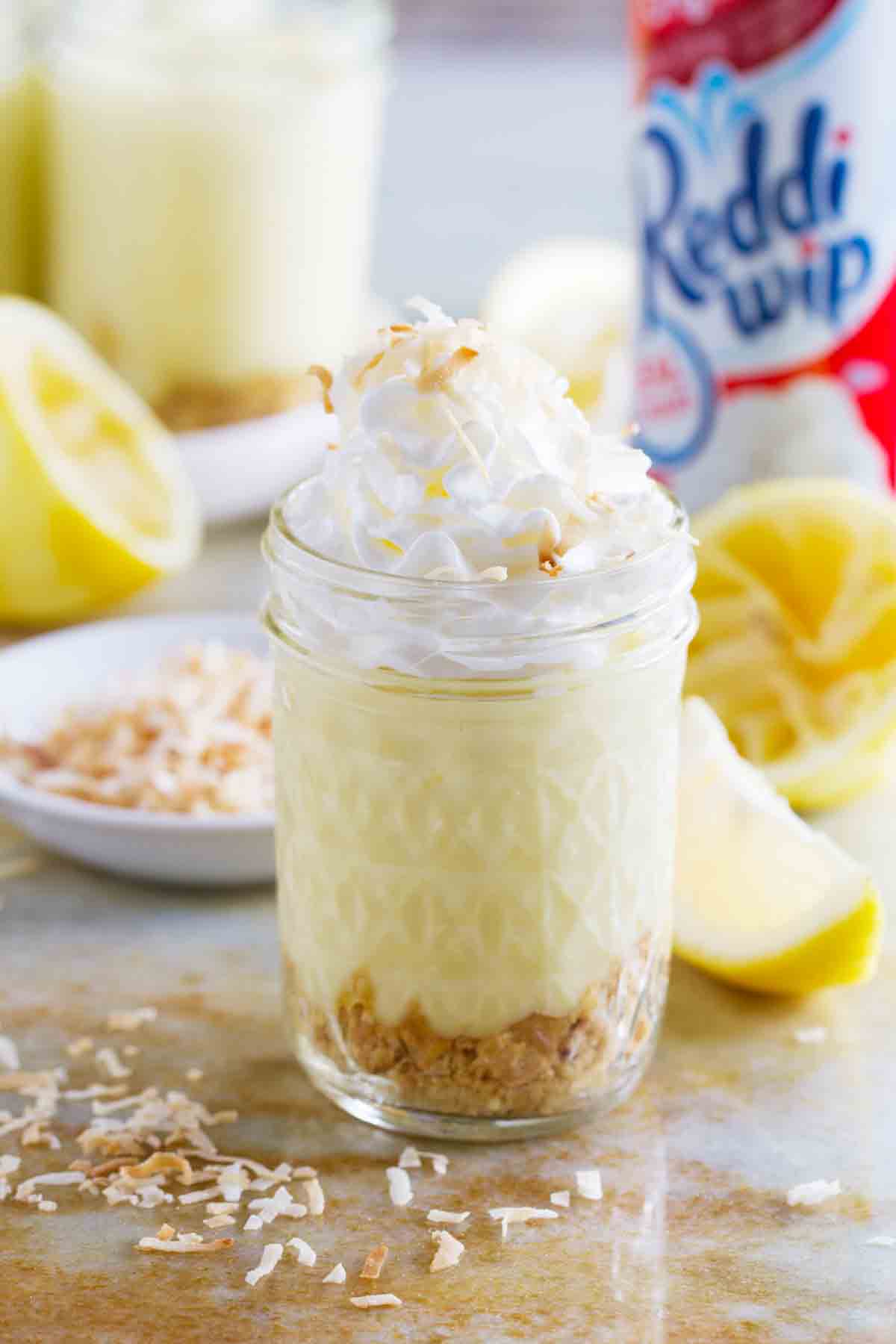 Jar with cookies, homemade lemon pudding, and whipped cream with toasted coconut.