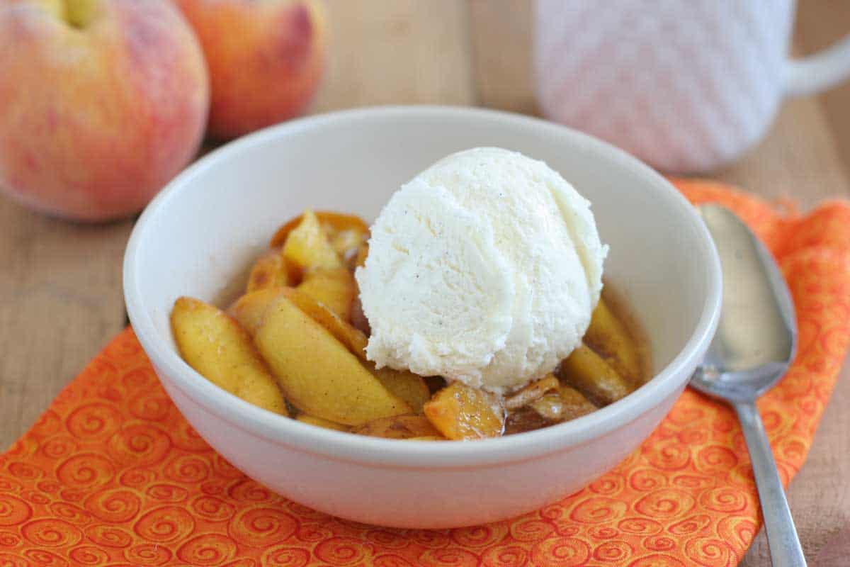 bowl of Crock Pot Peaches topped with vanilla ice cream