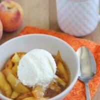 bowl of warm peaches cooked in the slow cooker topped with ice cream