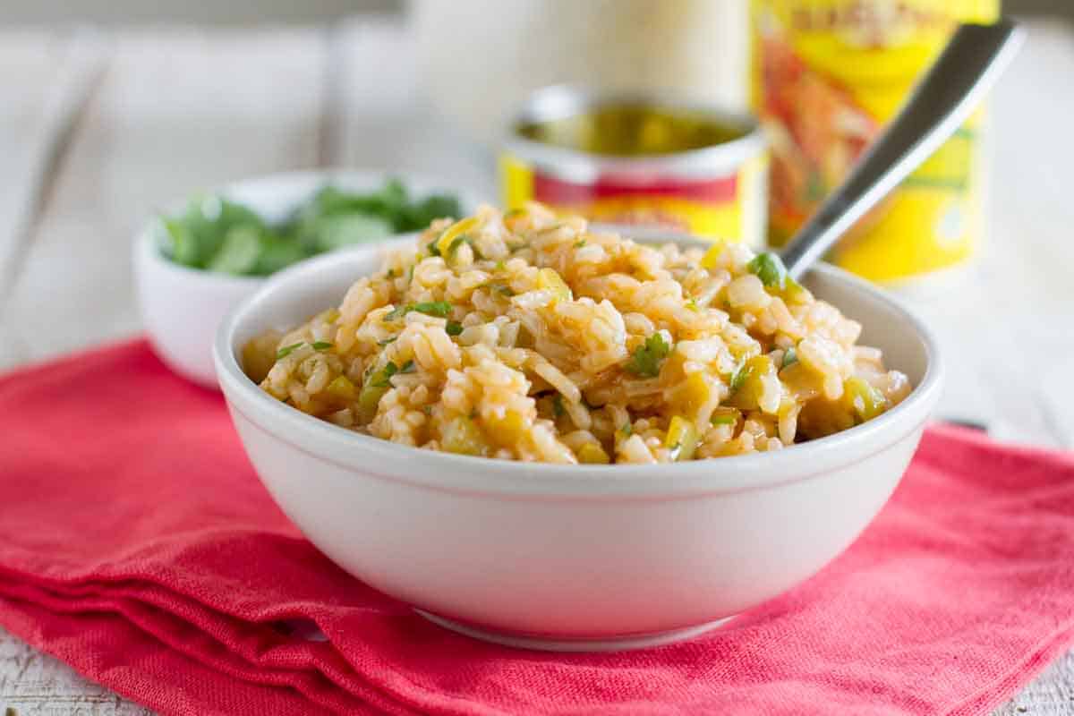 Bowl of Enchilada Rice on a towel with ingredients in the background.