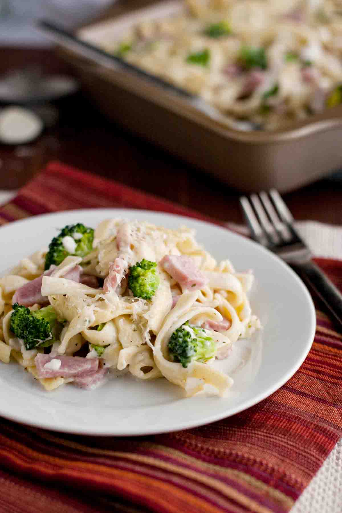 Ham and Broccoli Pasta Bake on a plate with the baking dish in the back.