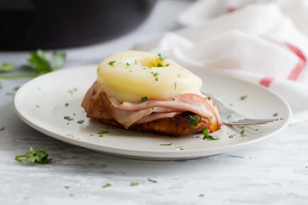 Hawaiian Chicken with Ham and Pineapple on a plate that is sprinkled with parsley.