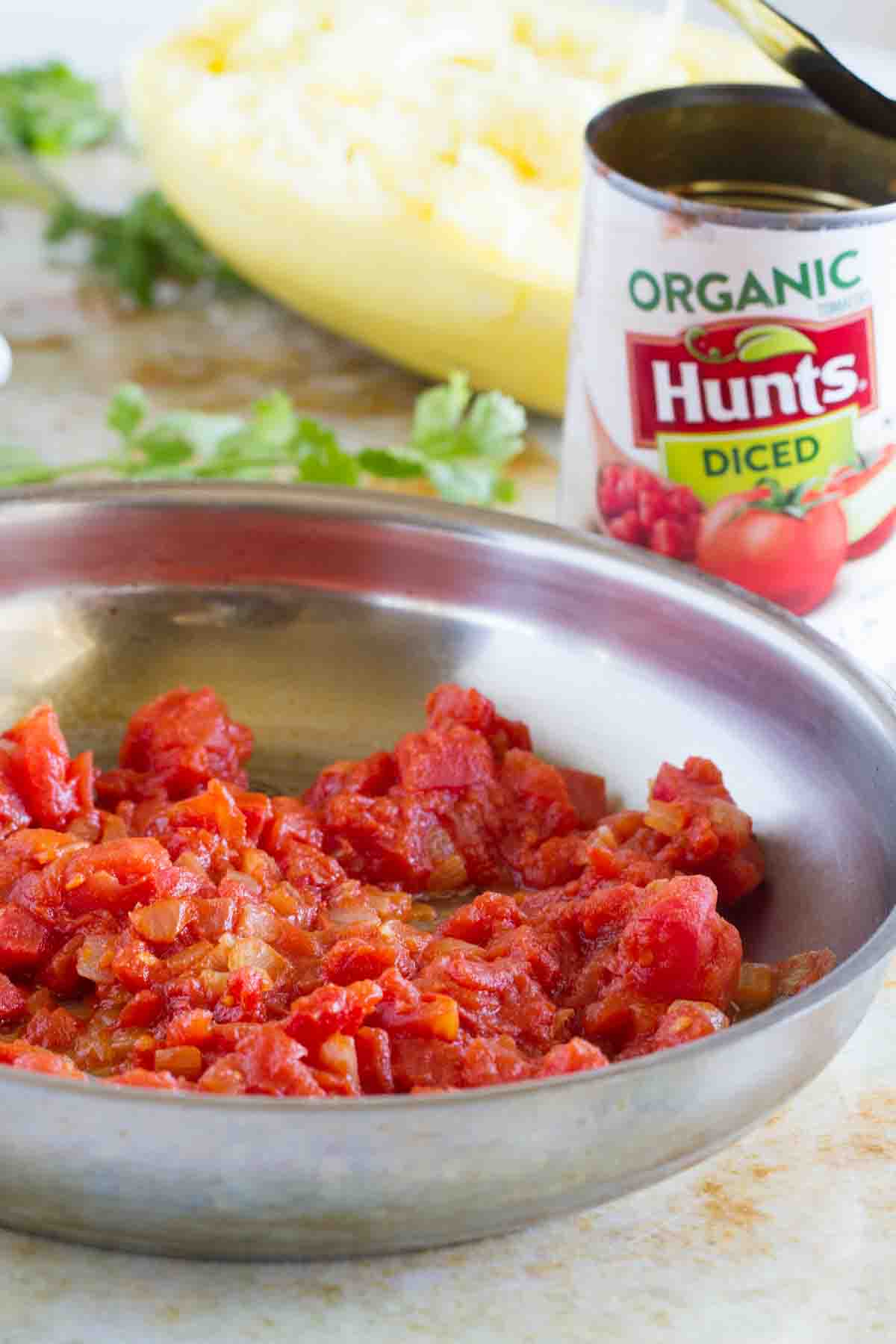 Cooking tomatoes with onions and spices in a skillet.