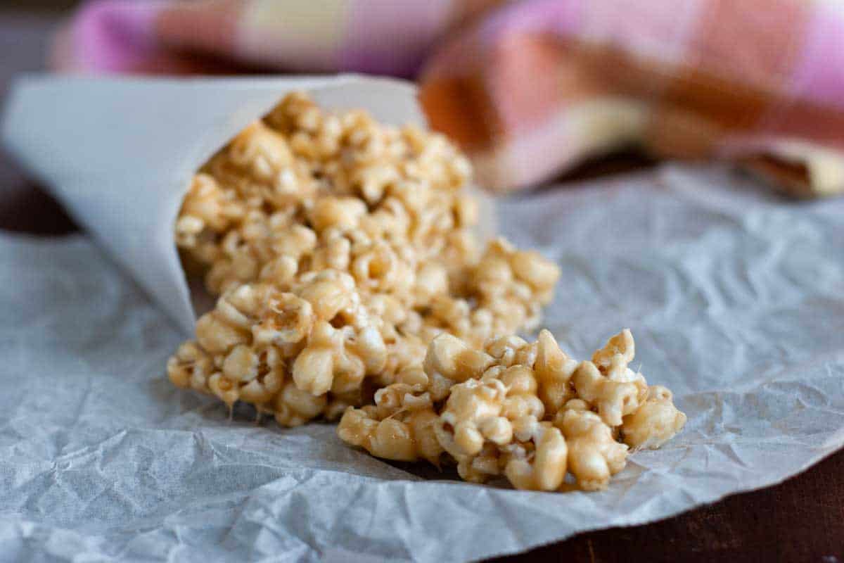Ooey and gooey, this Marshmallow Caramel Popcorn is coated with a marshmallow and caramel mixture, making it addictive and delicious. Marshmallow Caramel Popcorn on a piece of parchment paper