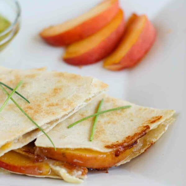 Peach and Brie Quesadillas on a plate with sliced peaches.