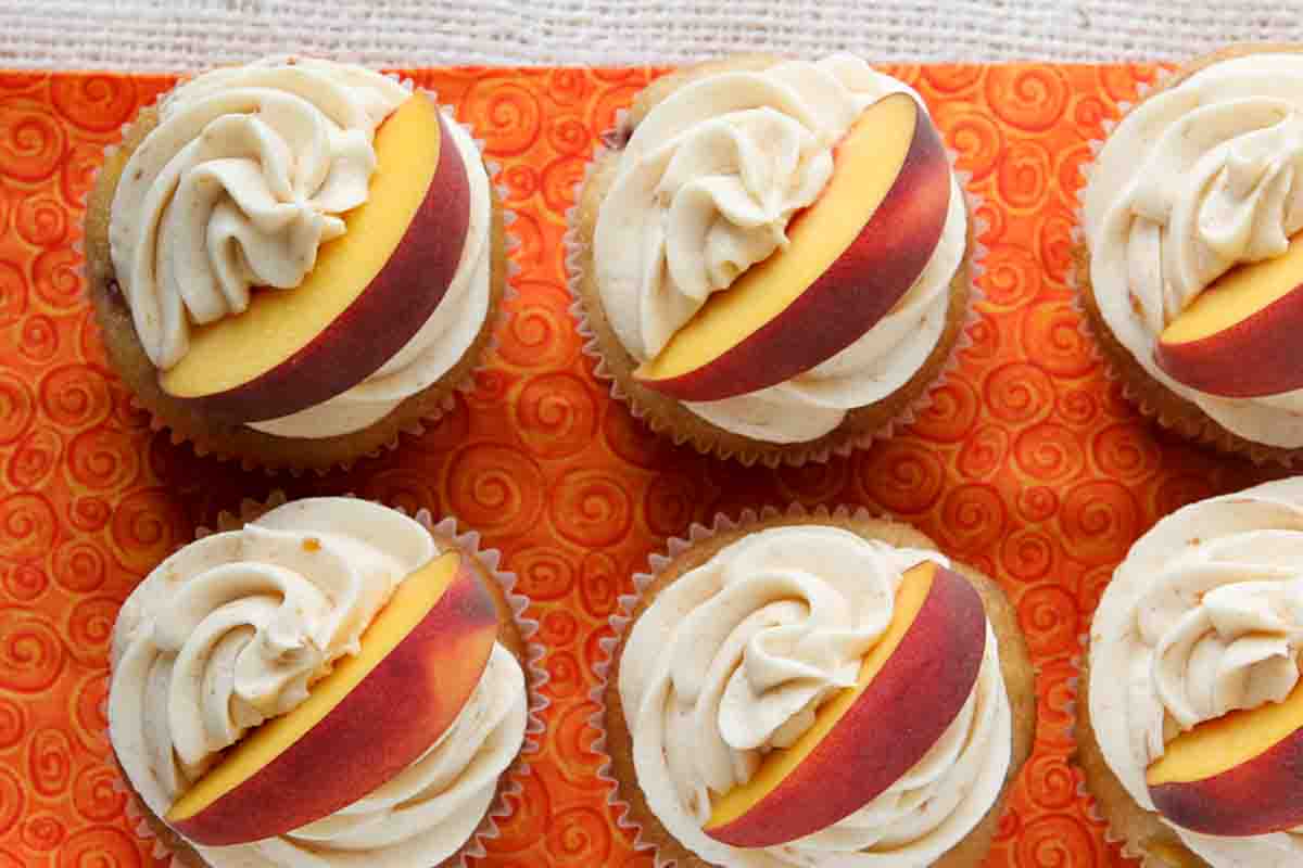 Peach Cupcakes topped with peach buttercream and a fresh peach slice