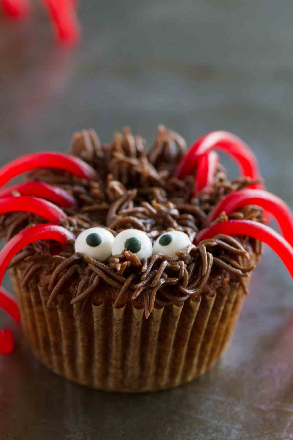 Cupcake topped with buttercream, candy eyes, and candy legs to resemble a spider.