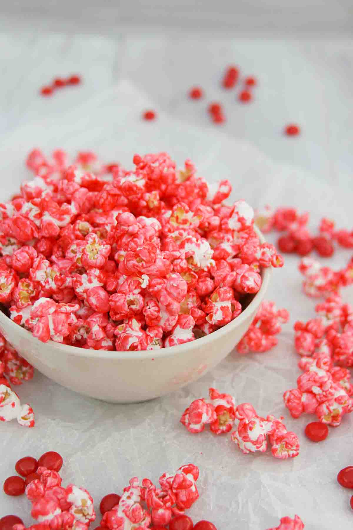 Red Hot Popcorn - spice up your popcorn with this easy cinnamon coated popcorn. bowl filled with Red Hot Popcorn with red hot candies around