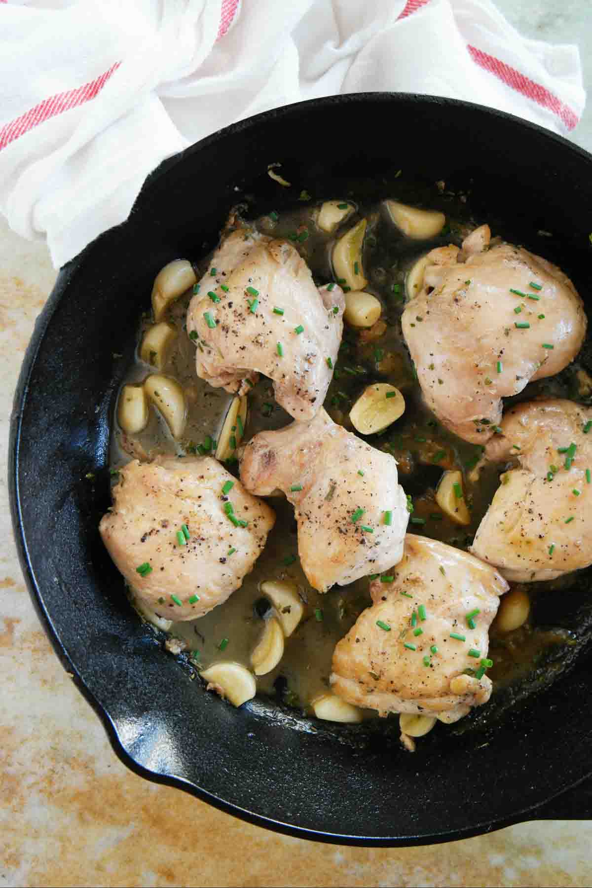 cast iron skillet with chicken thighs, garlic, and herbs.