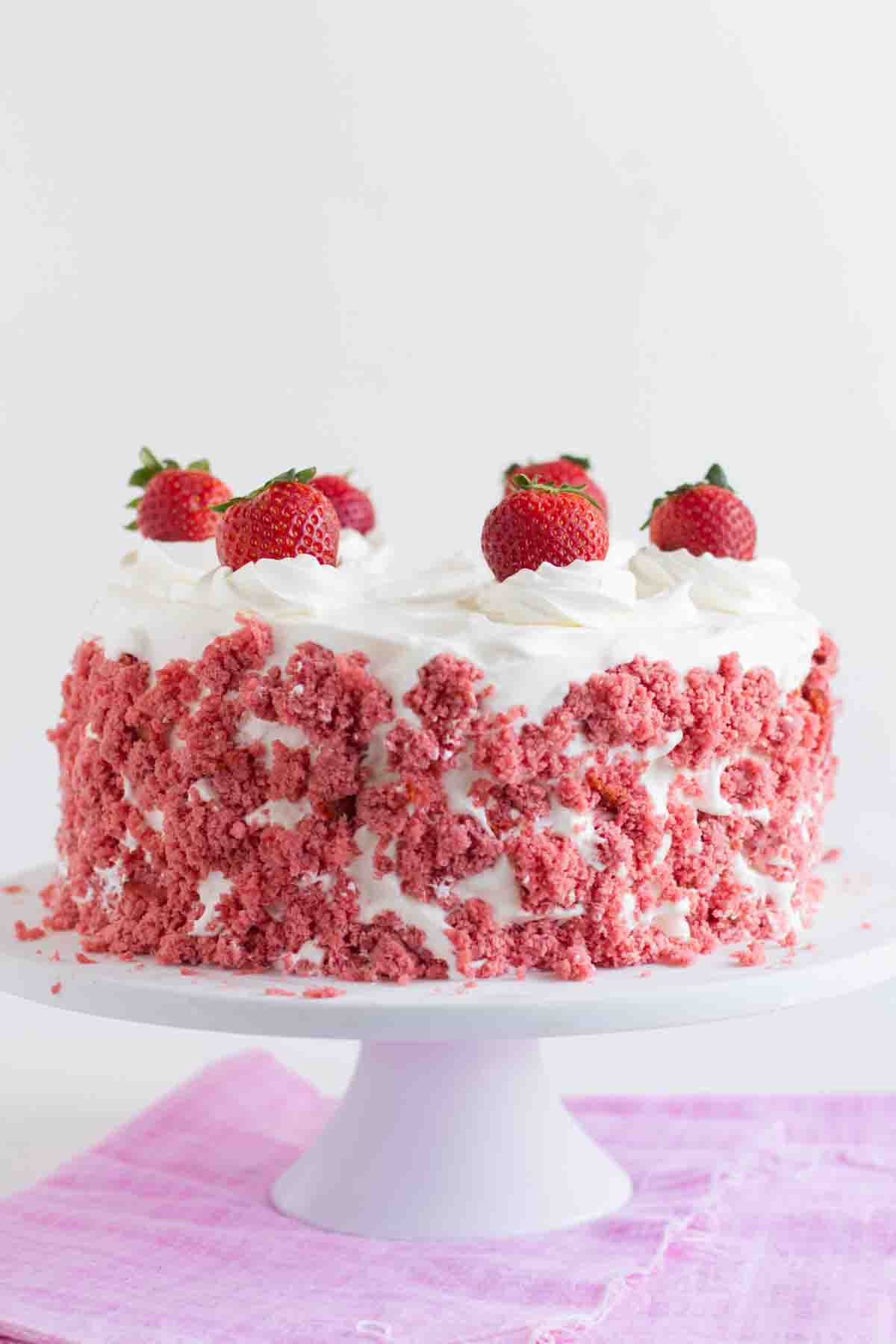 Full Strawberry Milkshake Ice Cream Cake on a cake stand topped with fresh strawberries.