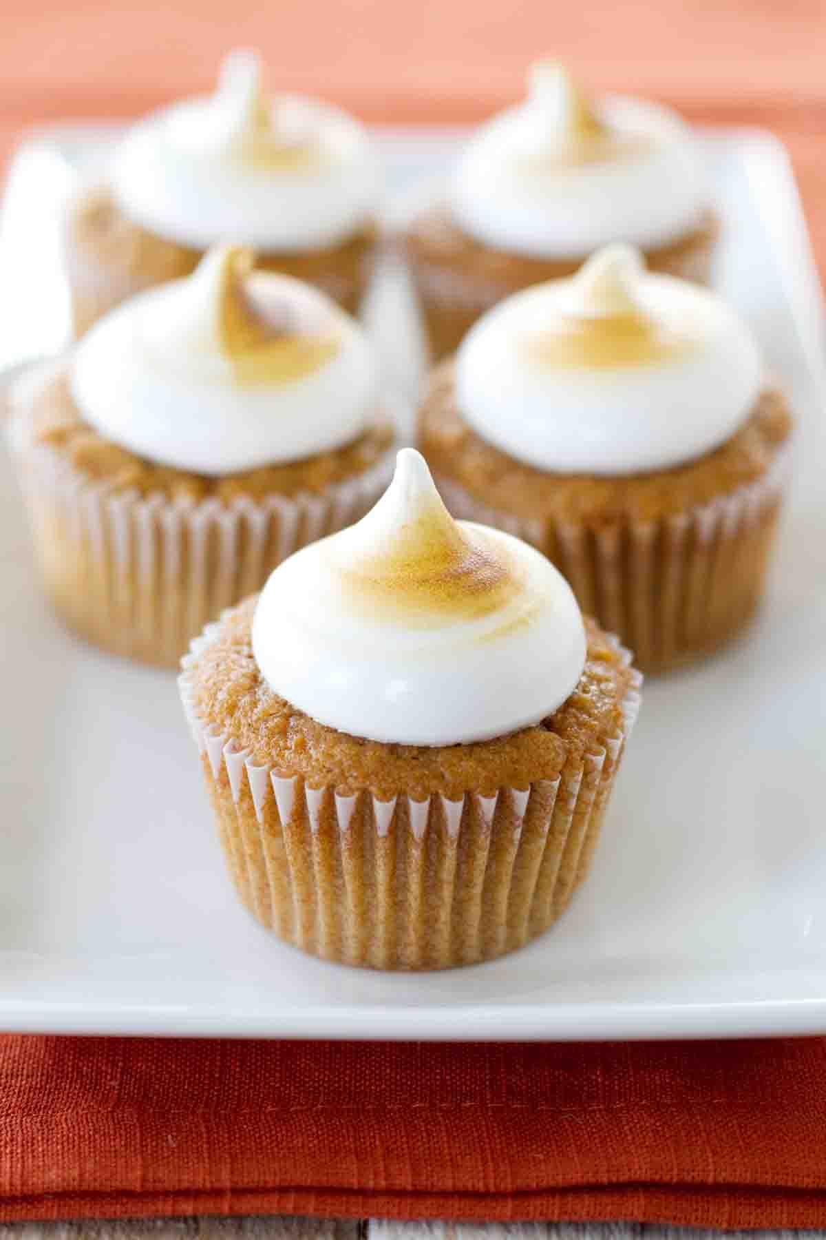 Forget the casserole and go straight for dessert! These moist, spiced Sweet Potato Cupcakes are topped with a marshmallow frosting, and then toasted to give them that familiar Thanksgiving flavor. A plate full of Sweet Potato Cupcakes that are topped with toasted marshmallow frosting.