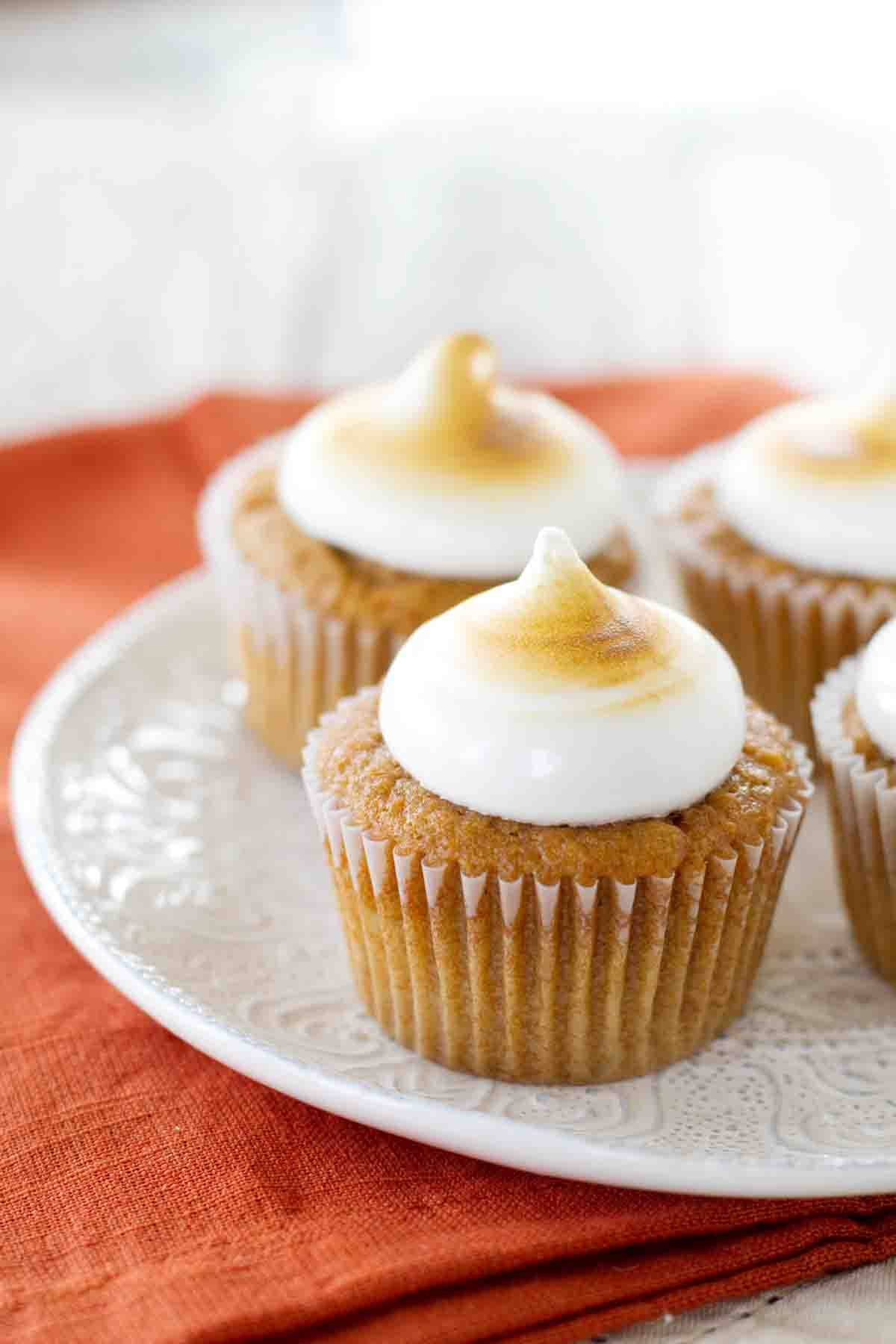 Sweet Potato Cupcakes topped with toasted marshmallow frosting on a white plate.