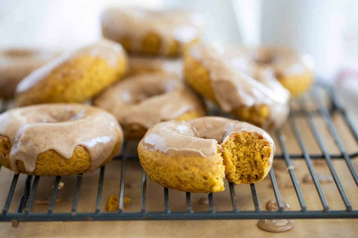 Baked Pumpkin Donuts on a cooling rack with a bite taken from one donut.