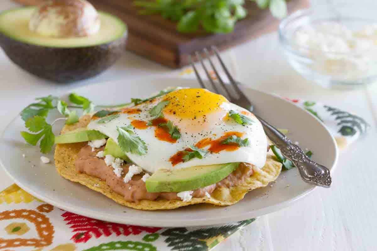 Breakfast tostada with beans, avocado and sunny side up egg.