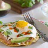Breakfast tostada on a plate with a fork.