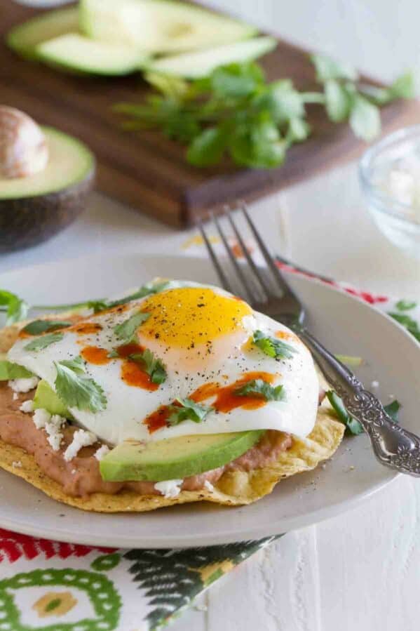 Breakfast tostada on a plate with a fork.